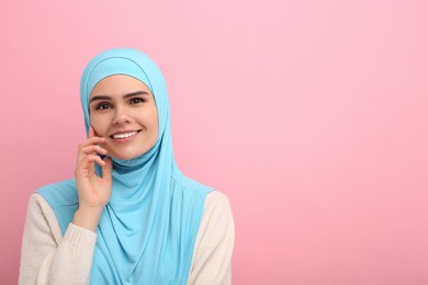Portrait of Muslim woman in hijab on pink background, space for text