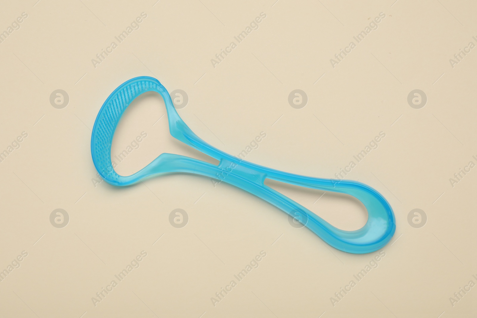 Photo of Light blue tongue cleaner on beige background, top view