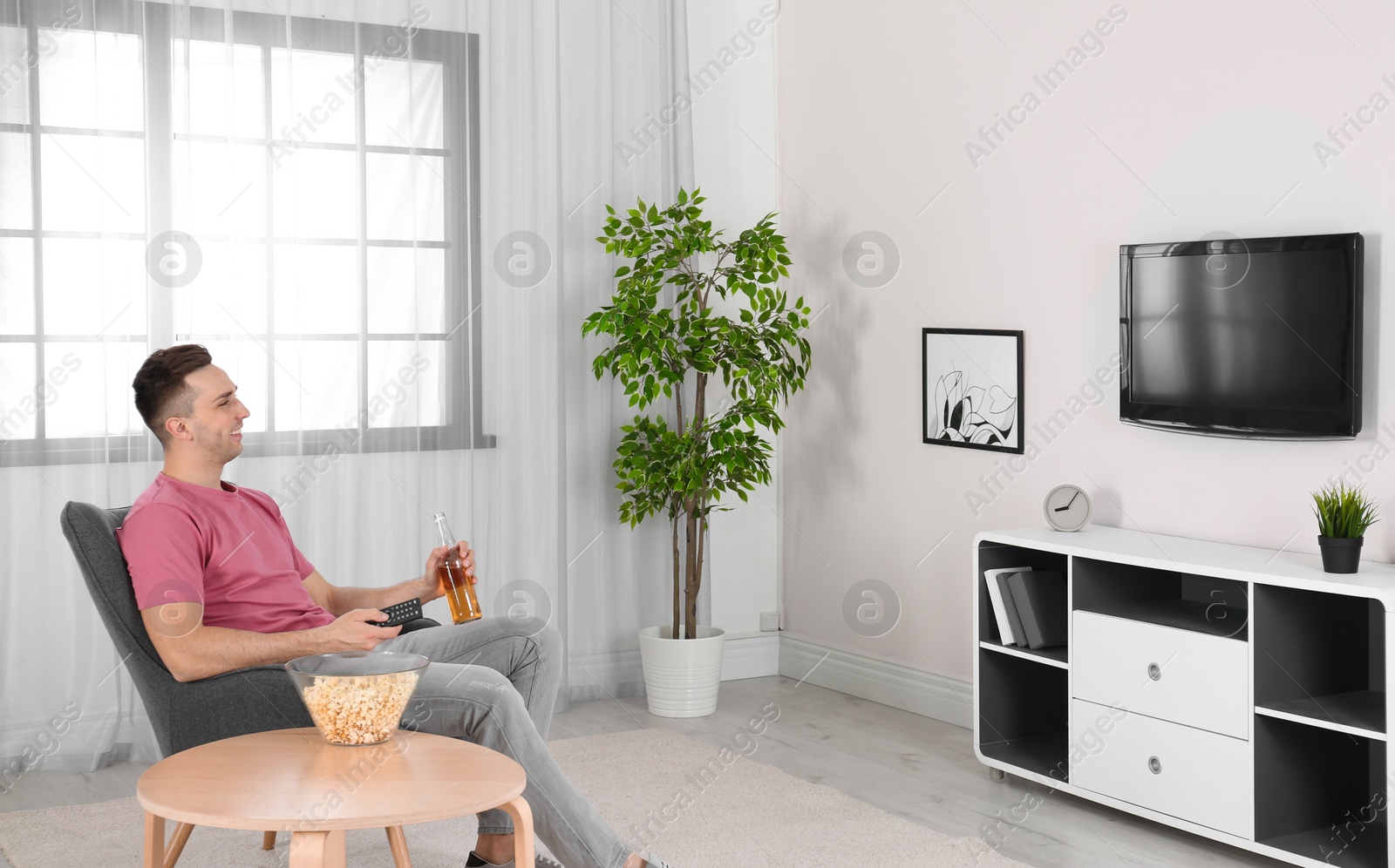 Photo of Handsome young man watching TV in armchair at home