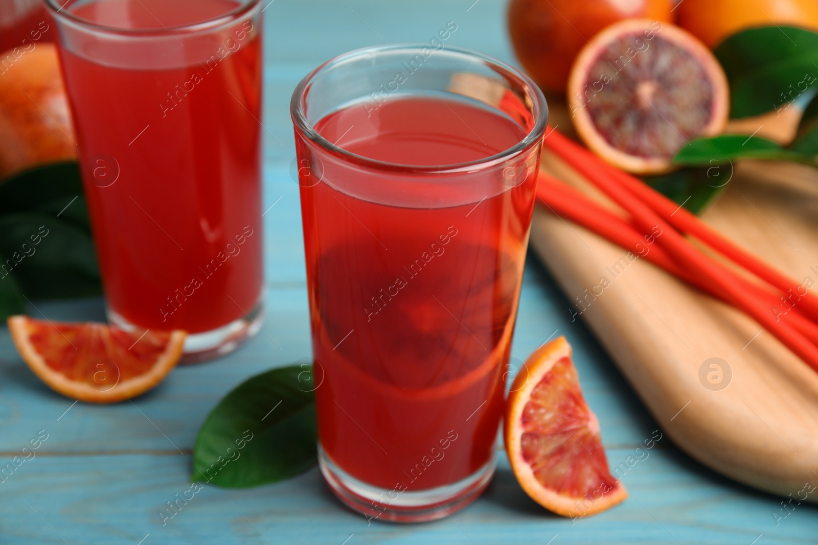 Photo of Tasty sicilian orange juice and fruits on light blue wooden table