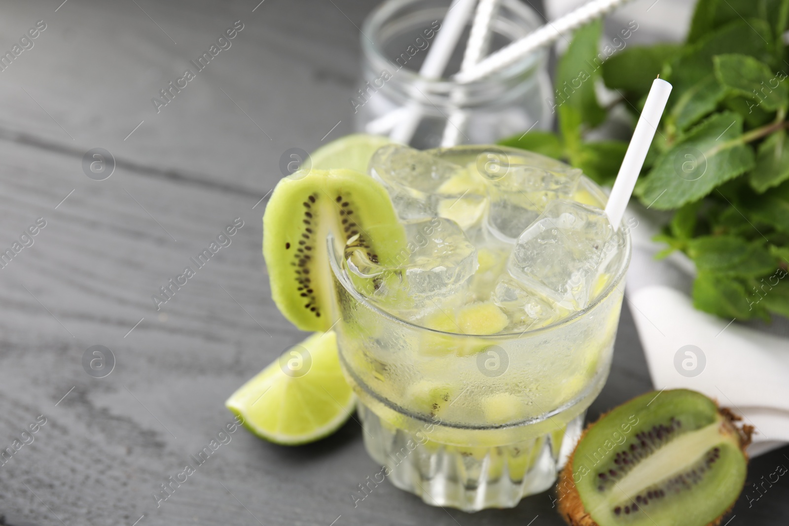 Photo of Glass of refreshing drink and cut kiwi on gray table, closeup