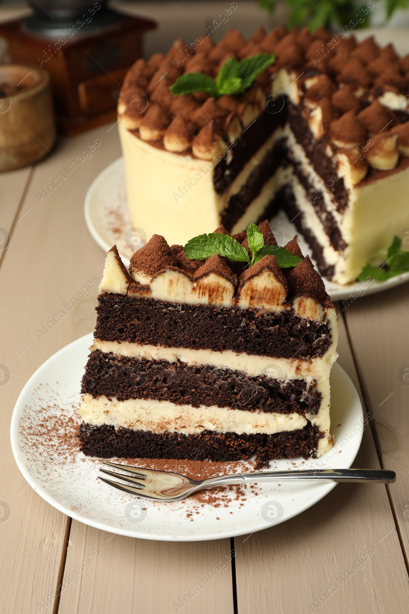 Photo of Piece of delicious tiramisu cake with mint leaves on wooden table