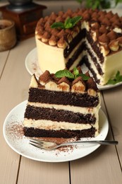 Photo of Piece of delicious tiramisu cake with mint leaves on wooden table