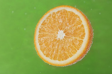 Photo of Half of orange in sparkling water on green background. Citrus soda