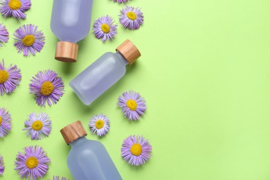 Photo of Flat lay composition with bottles of essential oil and daisy flowers on light green background. Space for text