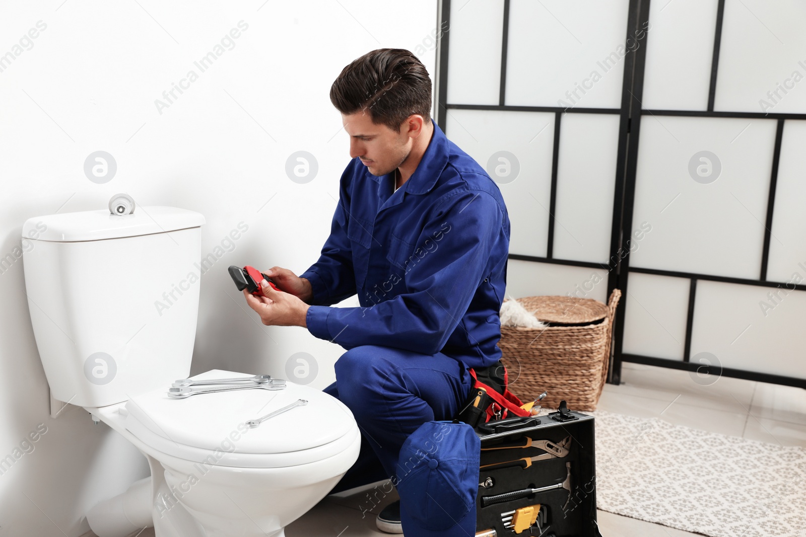 Photo of Professional plumber working with toilet bowl in bathroom