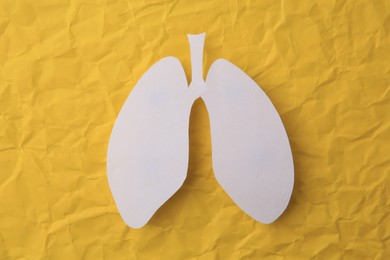 Paper in shape of human lungs on yellow crumpled background, top view