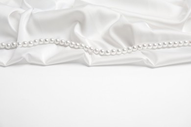 Beautiful pearls and delicate silk on white background