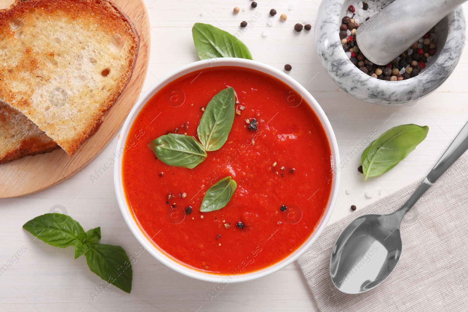 Photo of Flat lay composition with delicious tomato cream soup in bowl on white wooden table