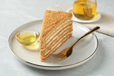 Photo of Slice of delicious layered honey cake served on grey table
