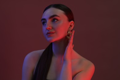 Photo of Portrait of beautiful young woman on color background in neon lights