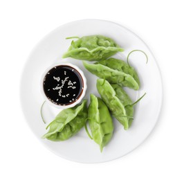 Delicious green dumplings (gyozas) and soy sauce isolated on white, top view