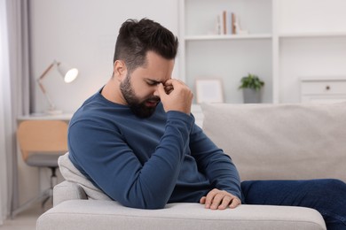 Photo of Man suffering from headache on sofa at home