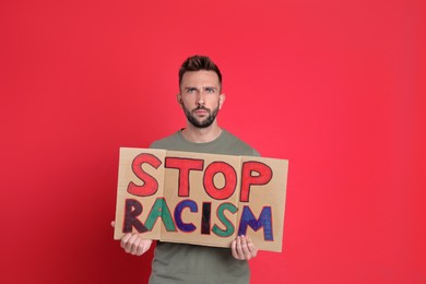Photo of Man holding sign with phrase Stop Racism on red background