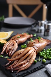 Photo of Tasty grilled squids served on black table, closeup