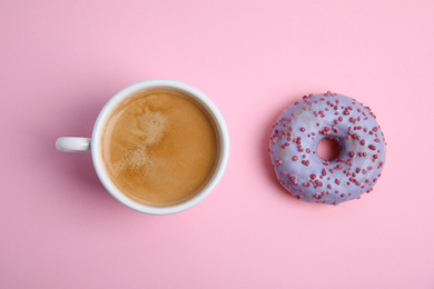 Delicious coffee and donut on light pink background, flat lay. Sweet pastries