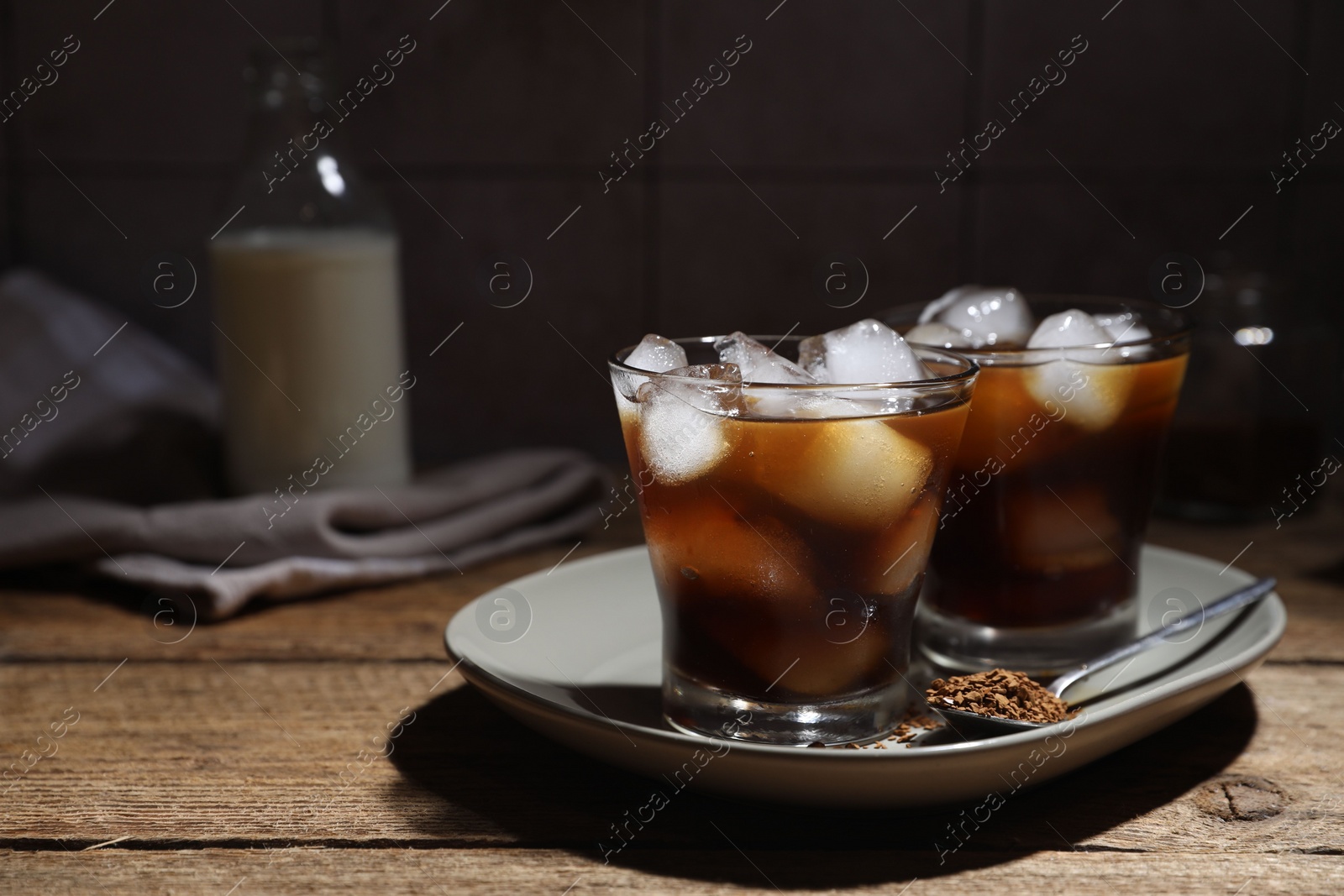 Photo of Refreshing iced coffee in glasses, ingredients and spoon on wooden table