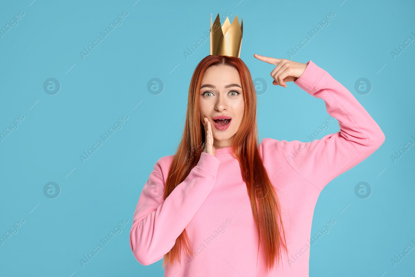 Photo of Emotional young woman with princess crown on light blue background