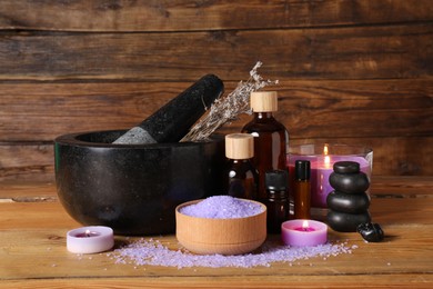 Photo of Beautiful composition with cosmetic products and burning candles on wooden table. Aromatherapy treatment