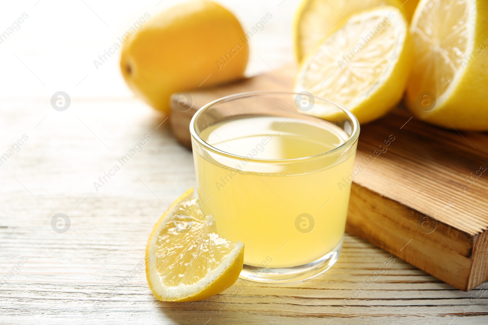 Photo of Glass with fresh lemon juice and fruits on table