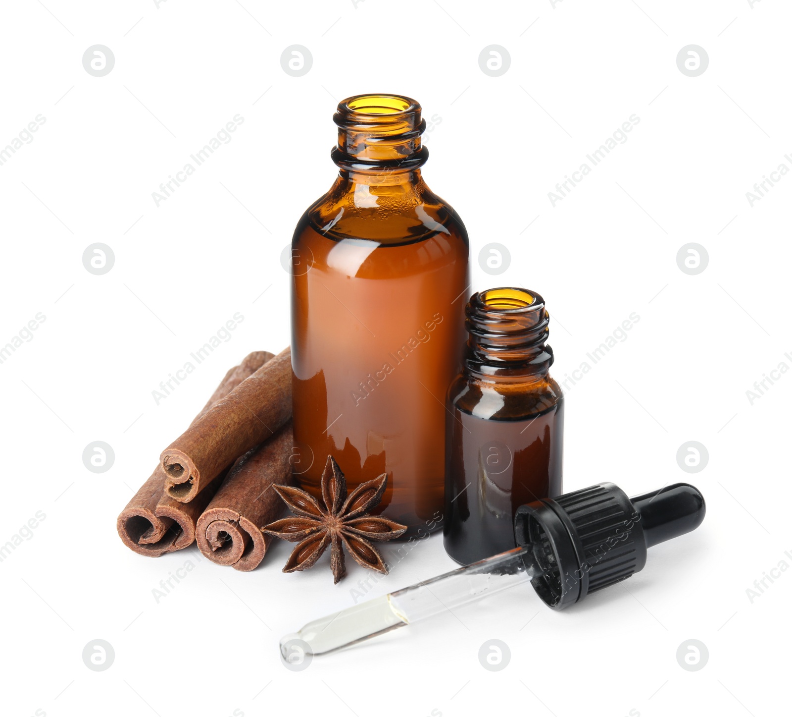 Photo of Bottles of essential oils and cinnamon sticks on white background