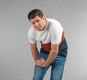 Photo of Young man suffering from pain in leg on grey background