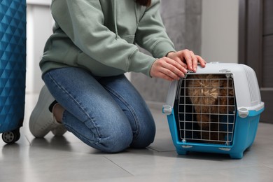 Photo of Woman closing carrier with her pet before travelling indoors, closeup