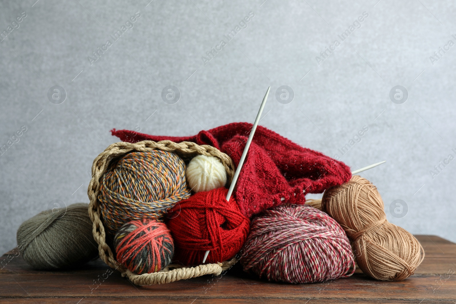 Photo of Soft woolen yarns, knitting and needles on wooden table