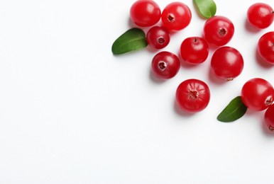 Photo of Fresh ripe cranberries and green leaves on white background, flat lay. Space for text