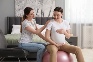 Doula taking care of pregnant woman in bedroom. Preparation for child birth