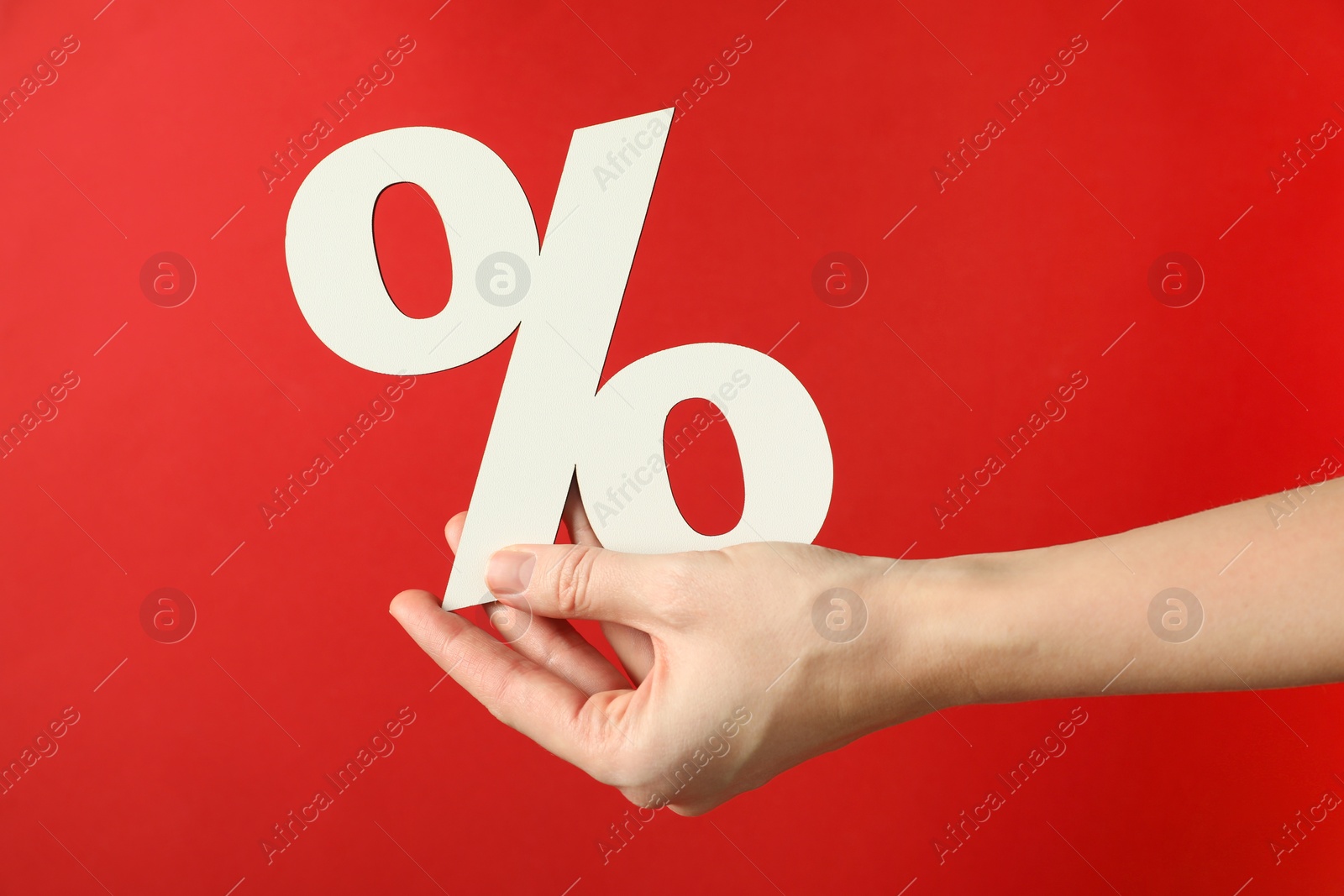 Photo of Woman holding percent sign on red background, closeup