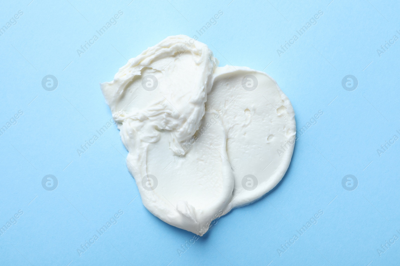 Photo of Smear of delicious cream cheese on light blue background, top view