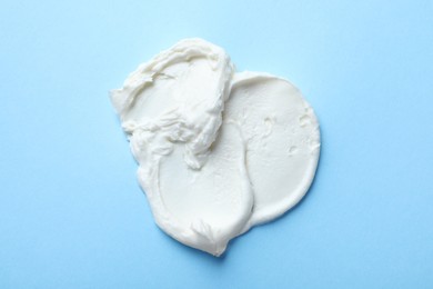 Photo of Smear of delicious cream cheese on light blue background, top view