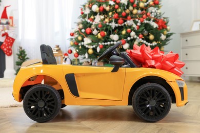Photo of Children's electric toy car with red bow in room decorated for Christmas