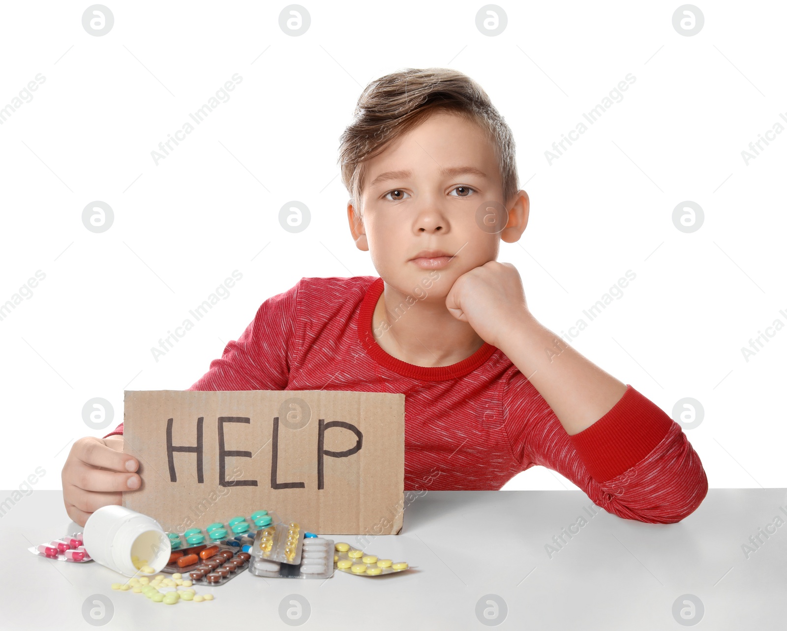 Photo of Little child with many different pills and word Help written on cardboard against white background. Danger of medicament intoxication