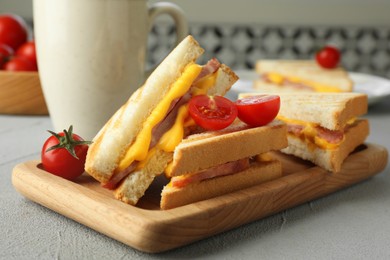 Tasty sandwiches with ham, melted cheese and tomatoes on grey textured table, closeup