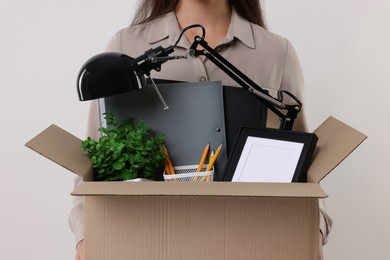 Photo of Unemployed woman holding box with personal office belongings on white background, closeup