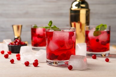 Photo of Tasty cranberry cocktail with ice cubes in glasses and fresh berries on wooden table