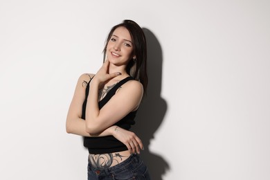 Photo of Portrait of smiling tattooed woman on light background