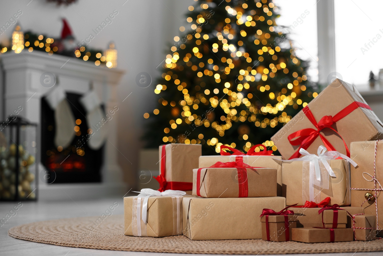 Photo of Many different gift boxes against blurred festive lights in living room, space for text. Christmas presents