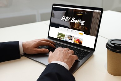 Man using laptop to book hotel at white table, closeup