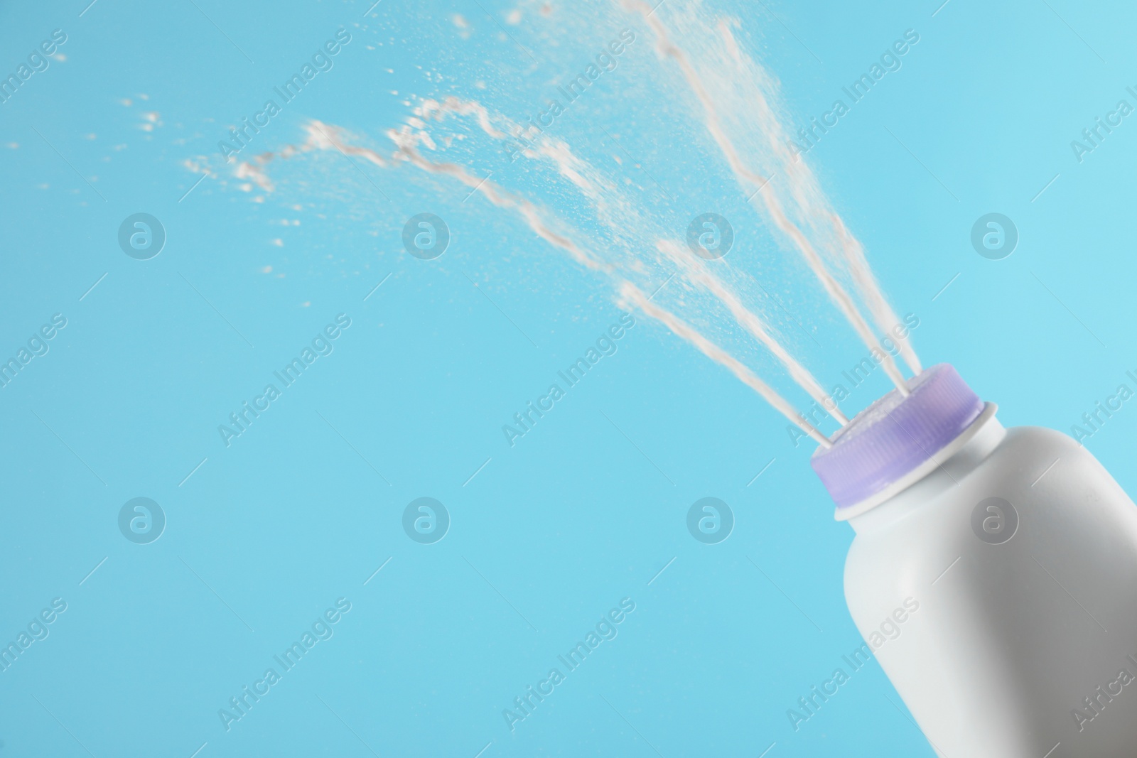 Photo of Scattering of dusting powder on light blue background, space for text