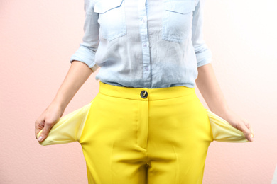 Photo of Woman showing empty pockets on pink background, closeup