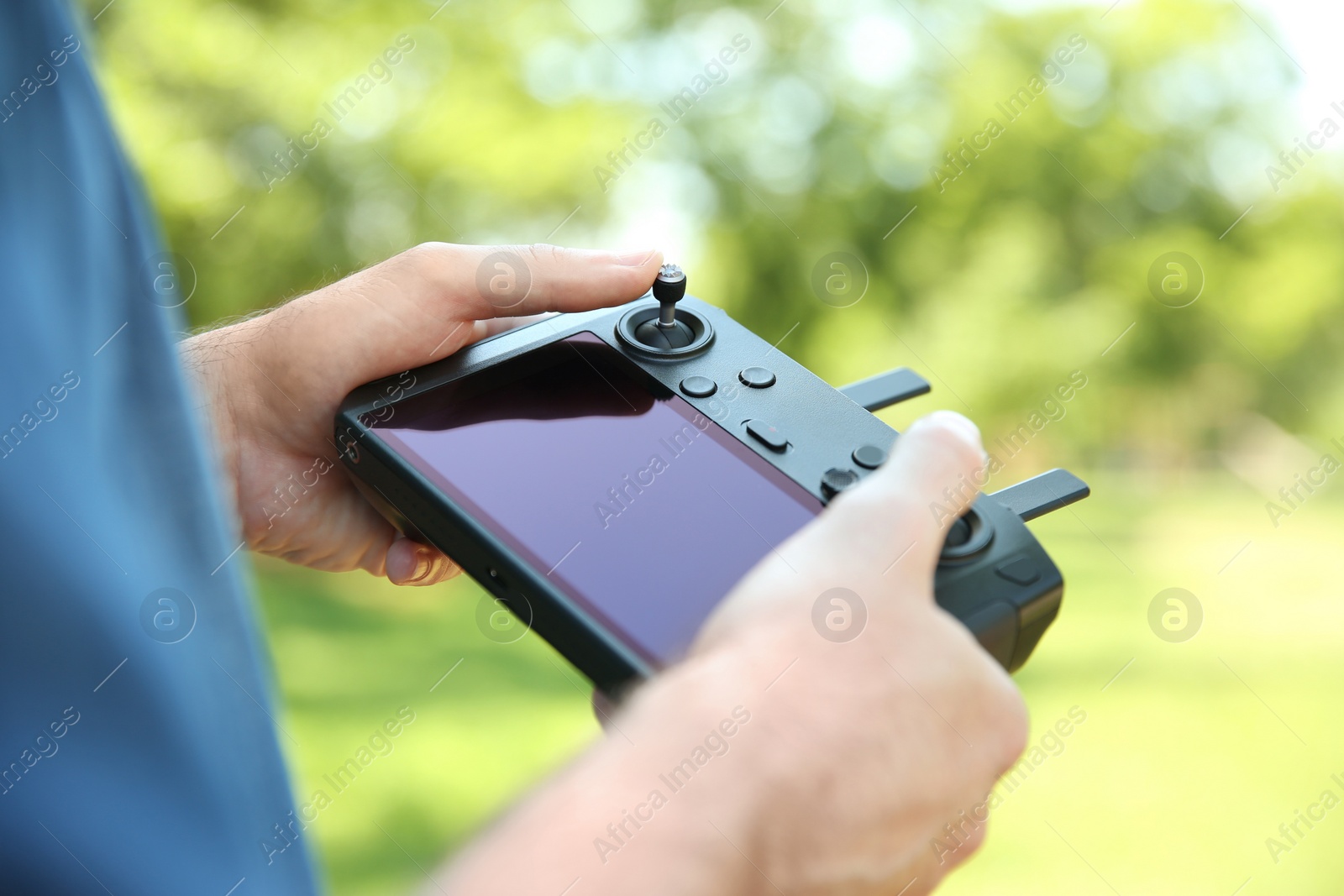 Photo of Man holding new modern drone controller outdoors, closeup of hands