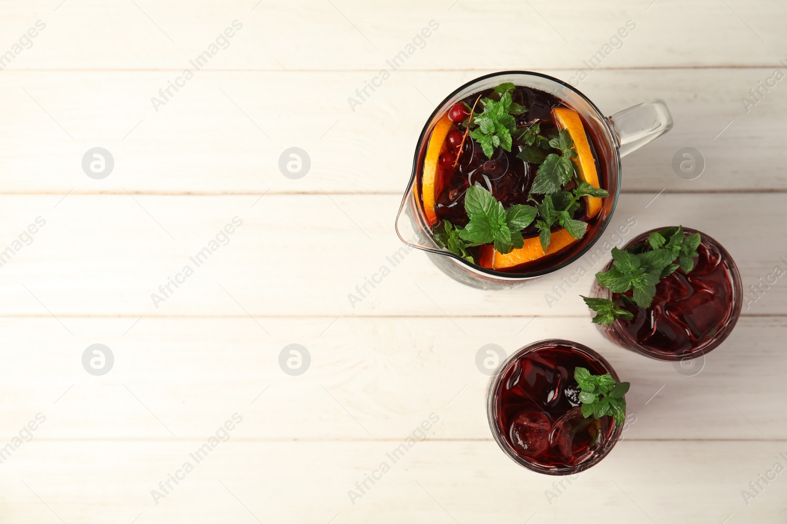 Photo of Glasses and jug with delicious cocktail on wooden table, top view