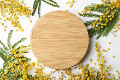 Beautiful mimosa flowers and wooden board on white background, flat lay. Space for text