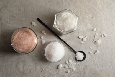 Photo of Different natural salt on grey textured table, flat lay