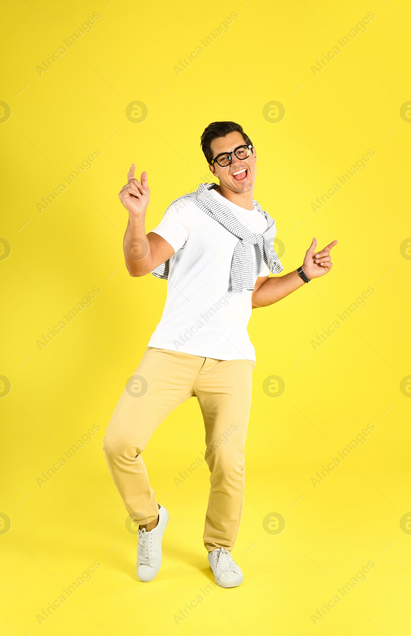 Photo of Handsome young man dancing on yellow background