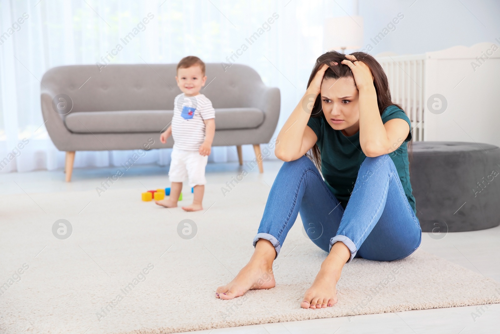 Photo of Young mother suffering from postnatal depression and little baby in room