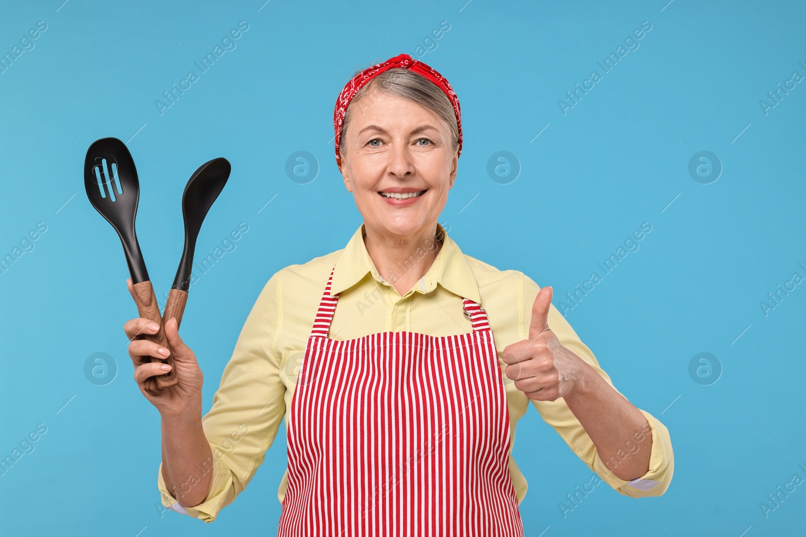 Photo of Happy housewife with spoons on light blue background